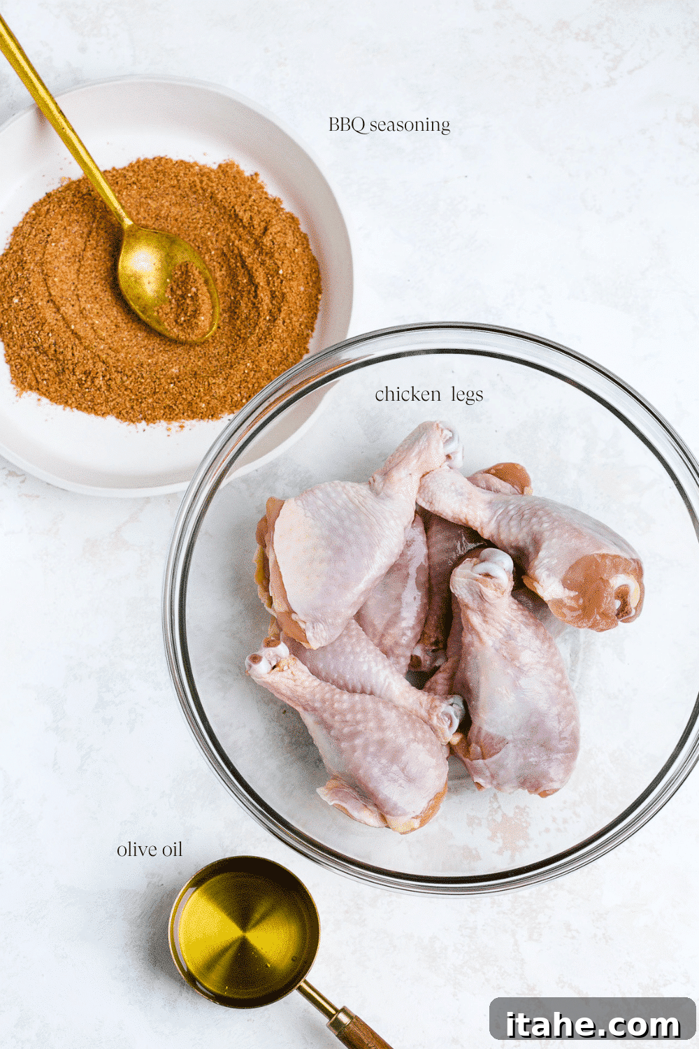 Perfectly Charred Chicken Legs 3 A vibrant display of ingredients for grilled chicken legs, featuring a bowl of raw chicken legs, a measuring cup of olive oil, and a white plate with a golden spoon displaying a rich blend of BBQ seasoning.