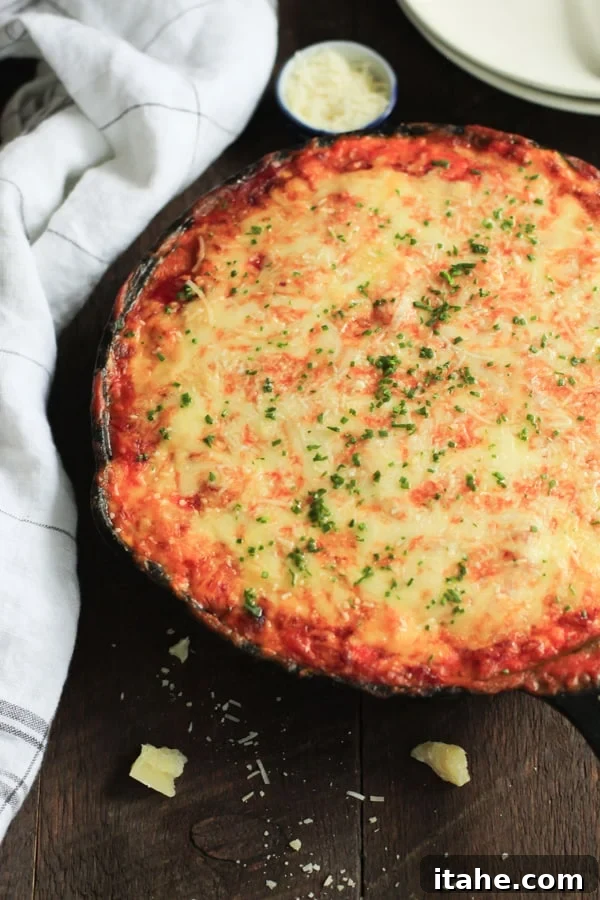 overhead view of a cast iron skillet containing zucchini lasagna, showing layers of zucchini, sauce, and cheese.