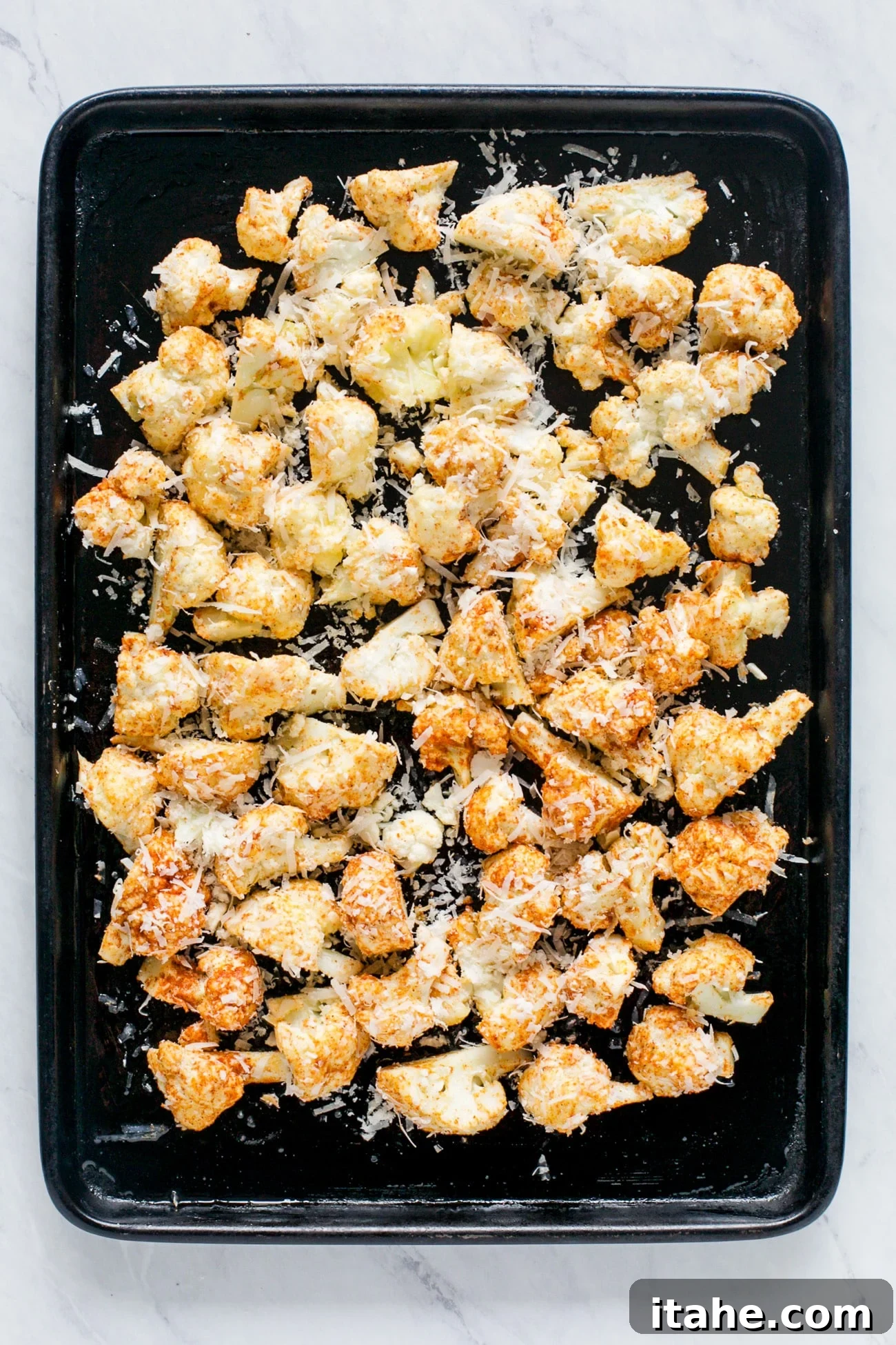 Crispy Cauliflower Poppers 5 Overhead view of seasoned cauliflower florets arranged in a single layer on a baking sheet, ready for roasting.