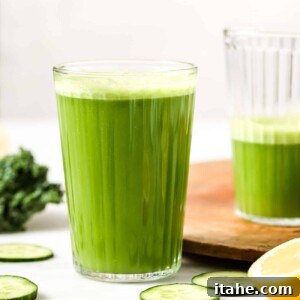 A perfectly portioned glass of fresh green juice, garnished with a slice of lime and fresh mint leaves, set against a bright, clean background.