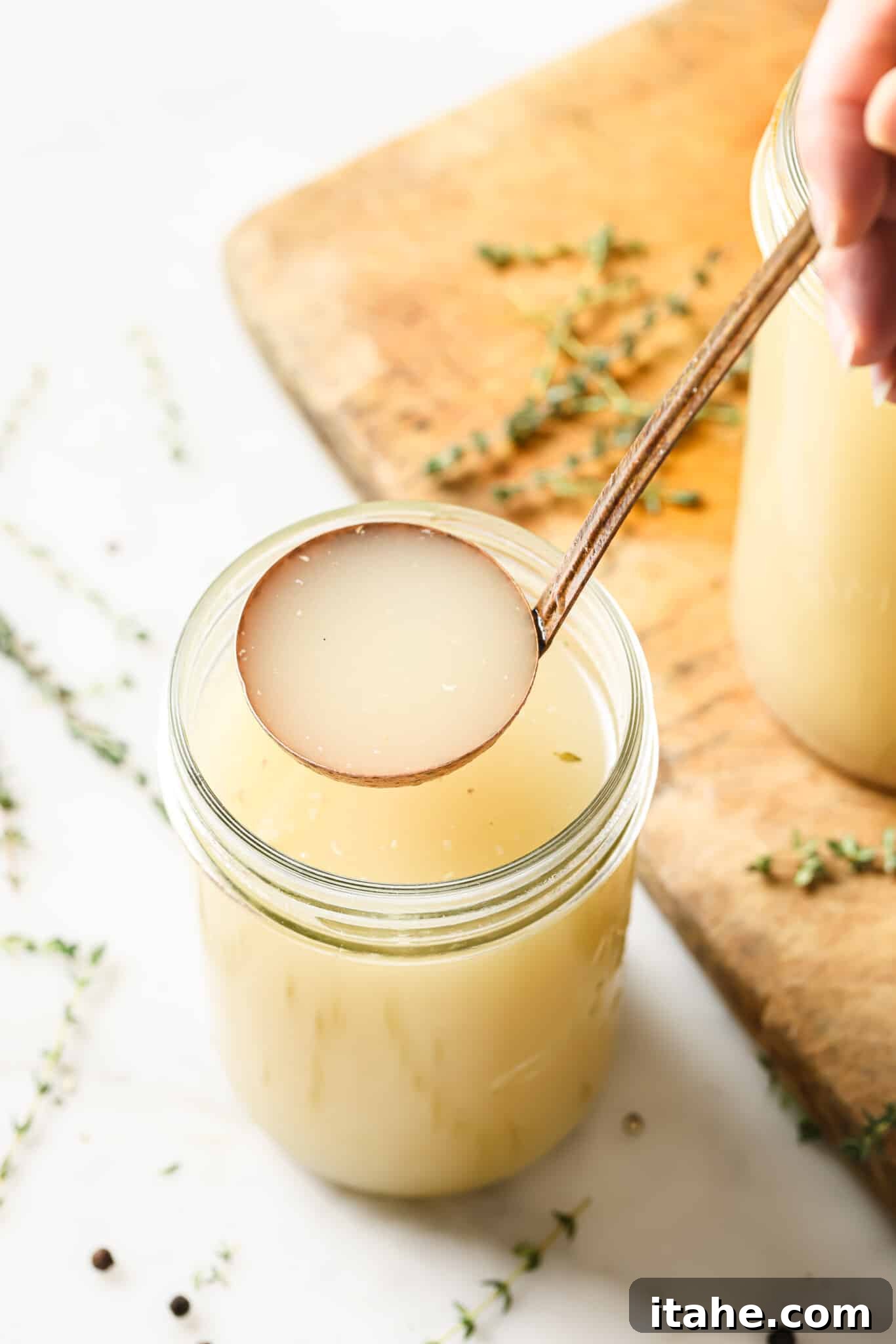A ladle serving turkey broth out of a mason jar.