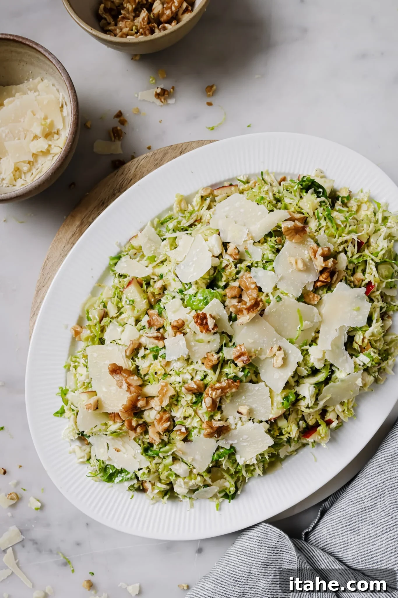 Shaved Brussels Sprouts Salad on a serving dish, garnished with walnuts and cheese.