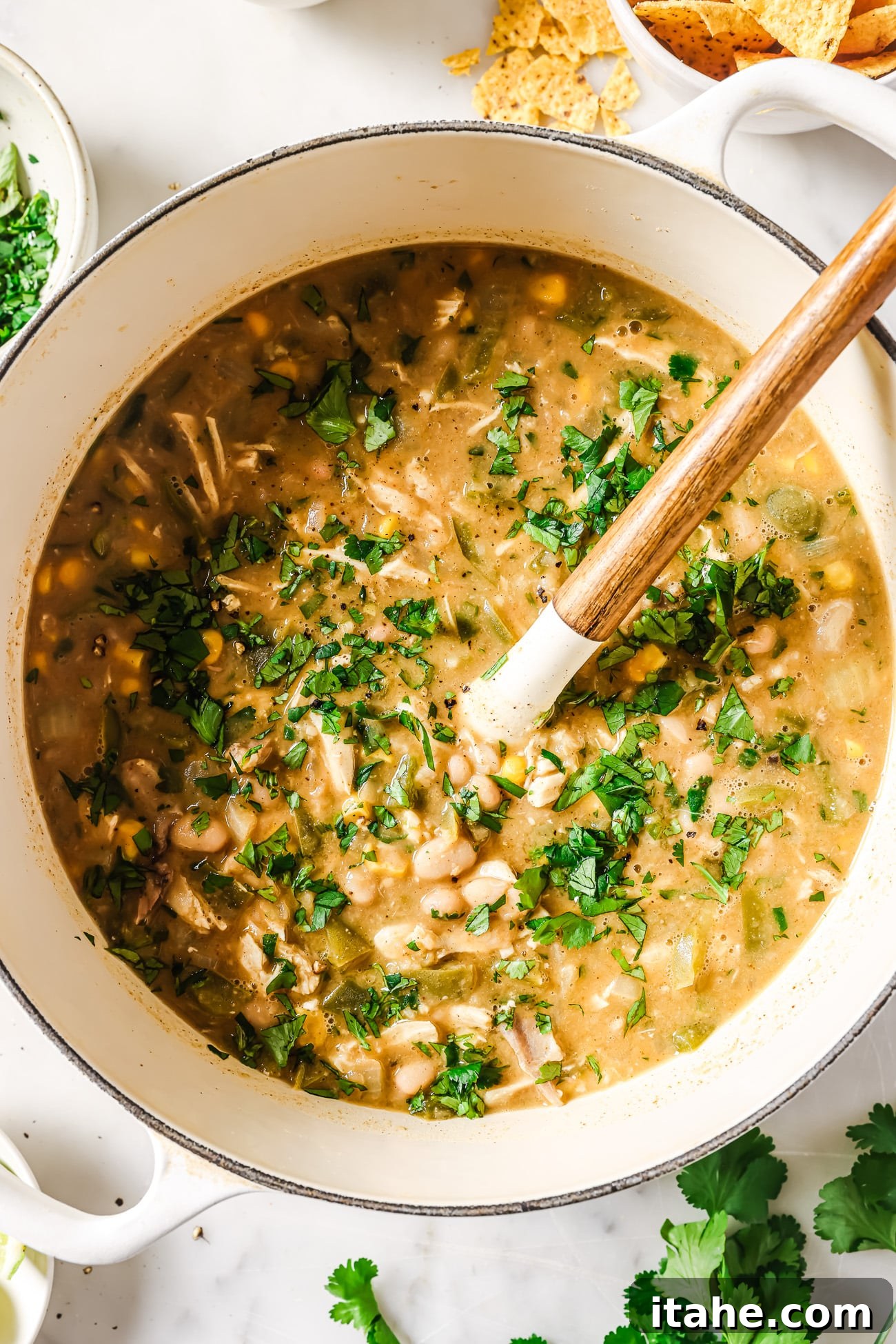 A Dutch Oven filled with savory White Chicken Chili, generously garnished with fresh cilantro, ready for serving.