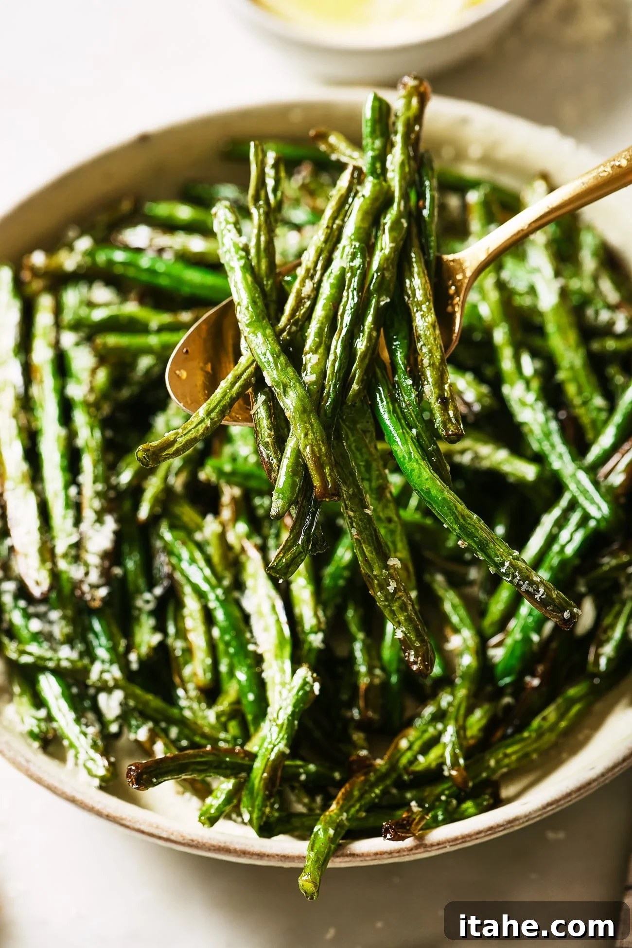 Perfectly Crispy Air Fryer Green Beans 8 A close up of air fryer green beans with a spoon dishing out a serving, showcasing their crispy texture.