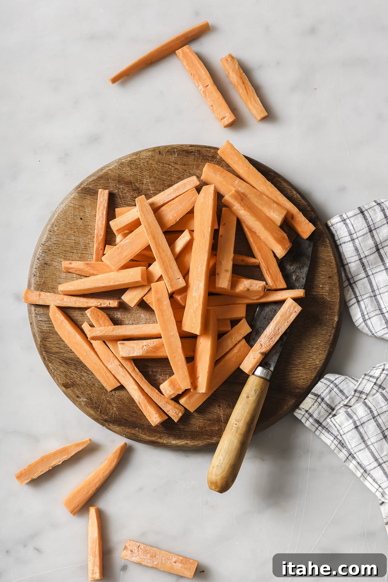 Perfectly Crispy Air Fryer Sweet Potato Fries 4 Sweet potatoes on a cutting board cut into sticks.