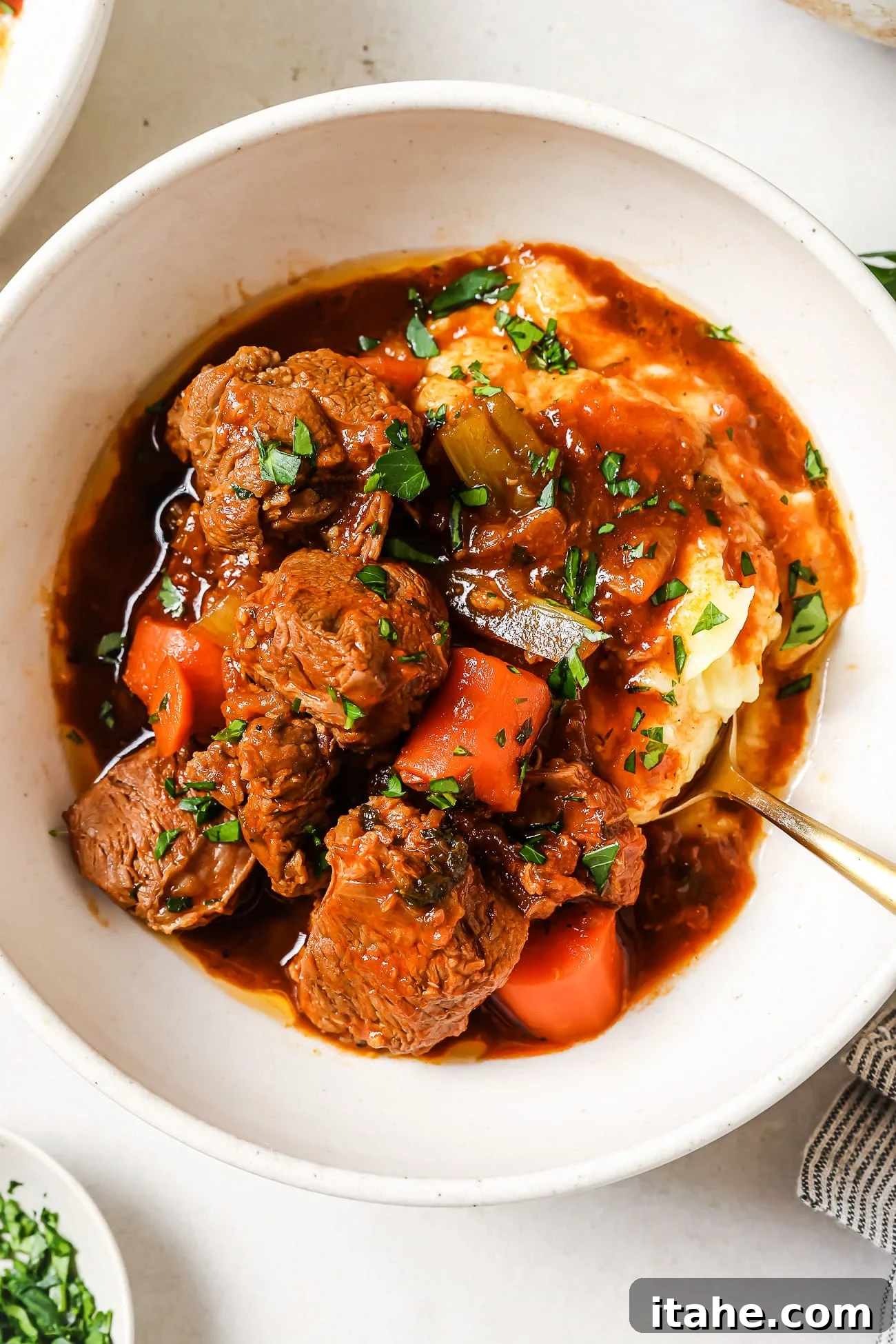 Hearty Lamb Stew 2 Lamb stew over mashed potatoes in a white bowl.