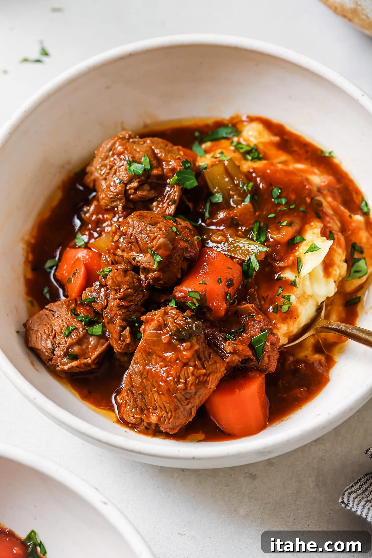 Hearty Lamb Stew 8 Lamb stew over mashed potatoes in a white bowl.