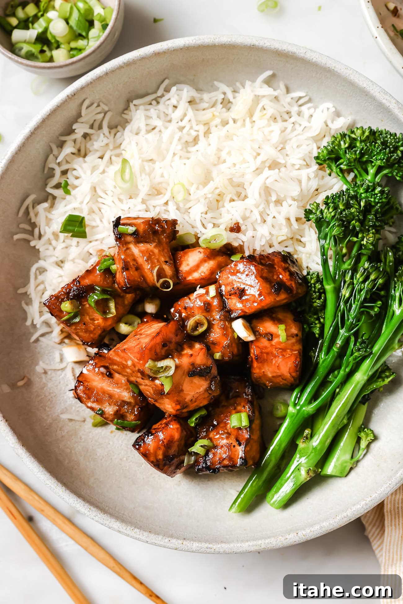 Golden Air Fryer Salmon Bites 2 Air fryer salmon bites on a plate with rice and broccoli, garnished with green onions.