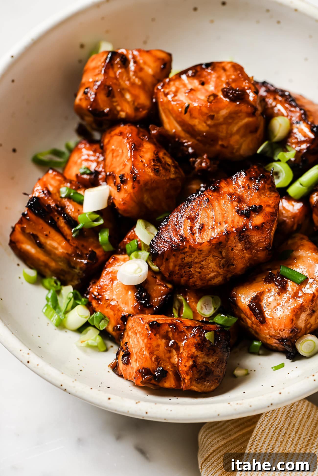 Golden Air Fryer Salmon Bites 6 Salmon bites in a bowl garnished with sesame seeds and green onions, ready to be served.