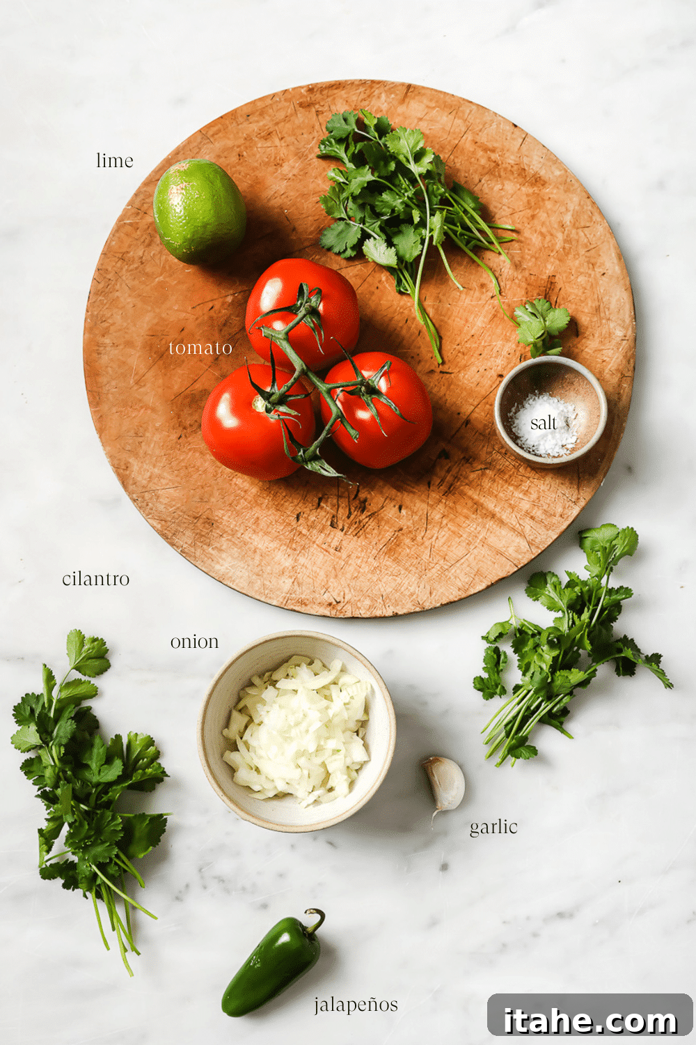 Ingredients on a wooden cutting board and white marble countertop.