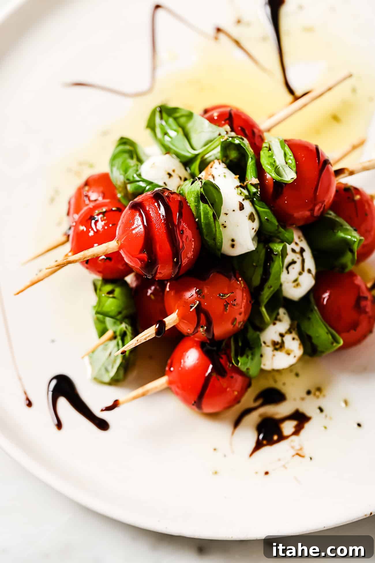 Several caprese skewers on a white serving plate.