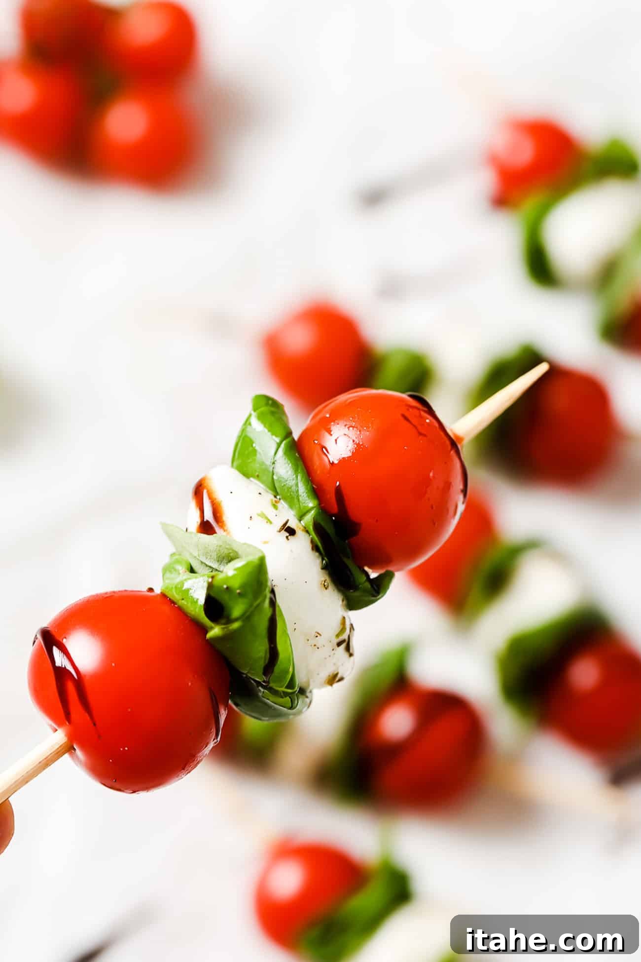 A closeup of one caprese skewer drizzled with balsamic reduction.