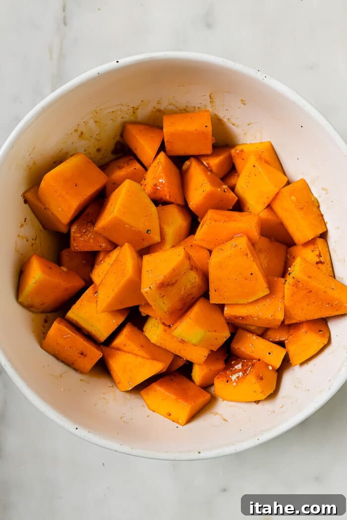An overhead view of the butternut squash coated in seasonings, glistening with olive oil.
