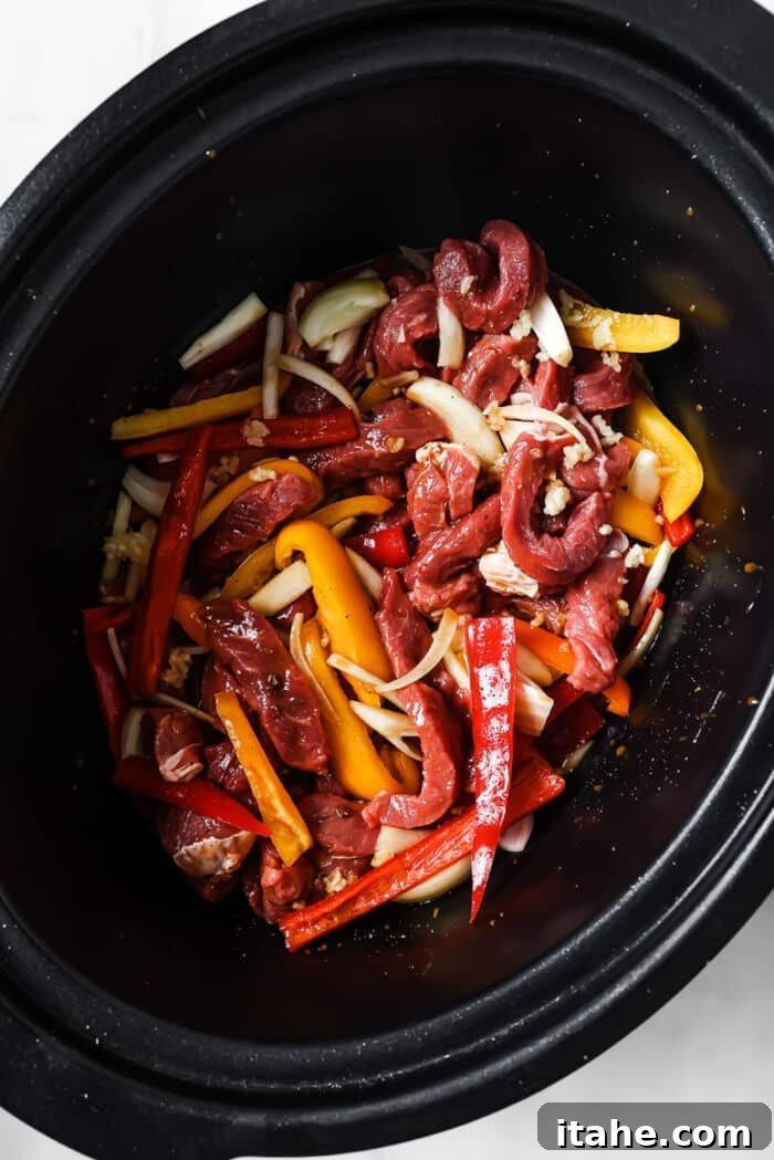 Slow Cooked Tender Pepper Steak 5 Bell peppers, onions, garlic, and sliced steak layered in the slow cooker.
