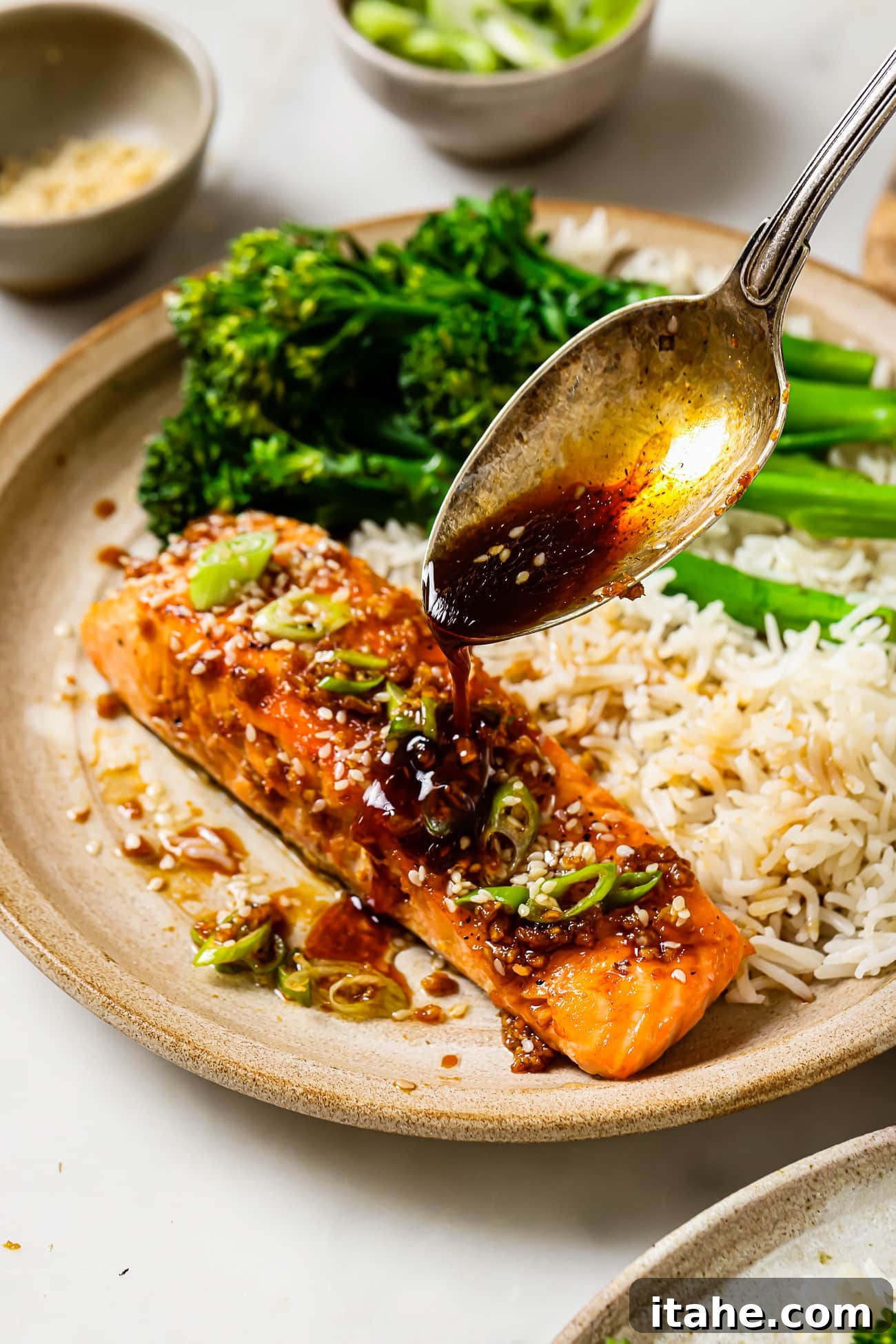 Garlic Honey Glazed Salmon 2 Honey Garlic Salmon with sauce spooned over it next to rice and brocollini.