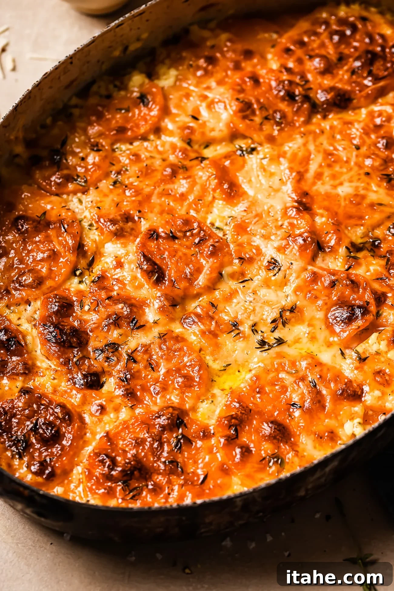 A closeup of sweet potato gratin in an oval casserole dish, showing the bubbly cheese and tender layers.