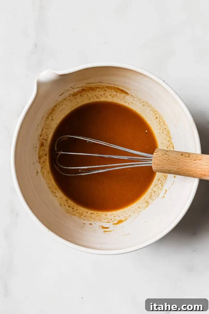 A vibrant chicken taco marinade being whisked to perfection in a white bowl, ensuring a smooth and lump-free consistency.