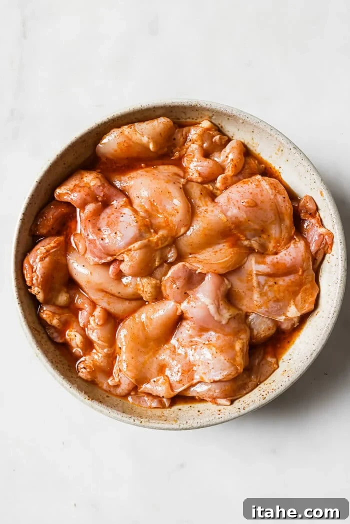 Tender chicken thighs fully coated with the vibrant, homemade marinade, resting in a large white bowl, absorbing all the zesty flavors.