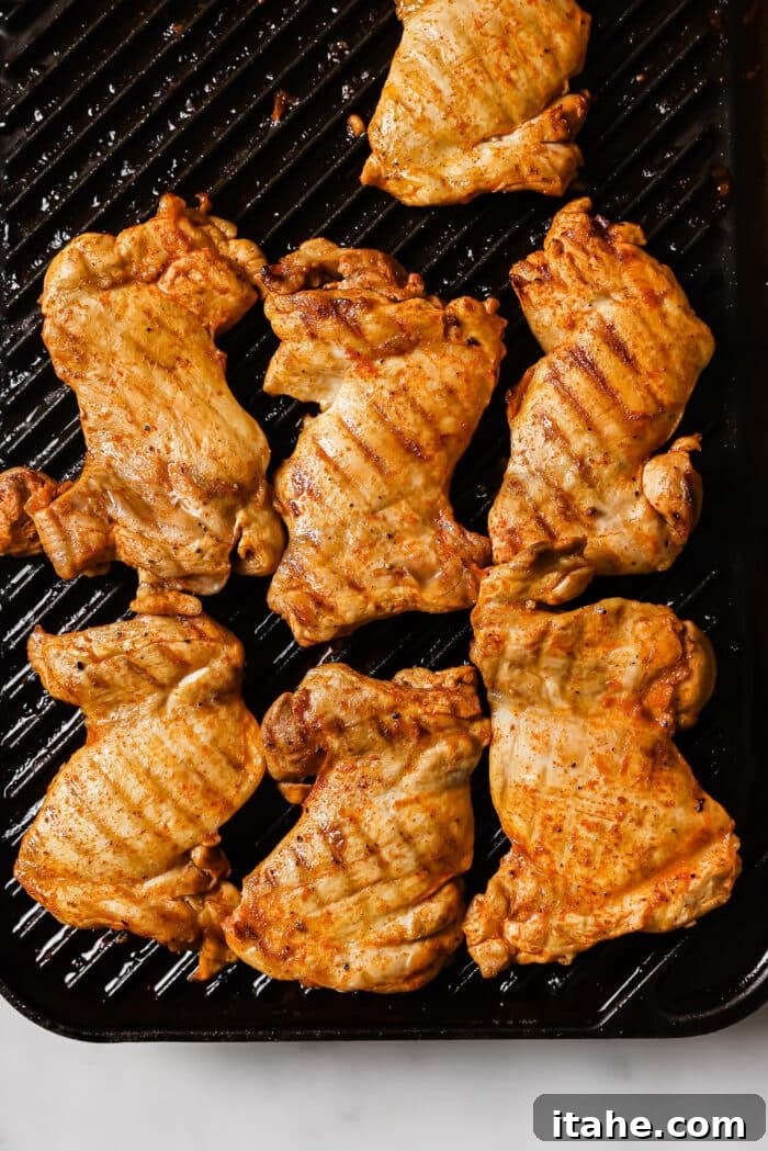 Juicy chicken thighs sizzling and cooking to perfection on a hot grill pan, developing a beautiful char and golden crust.