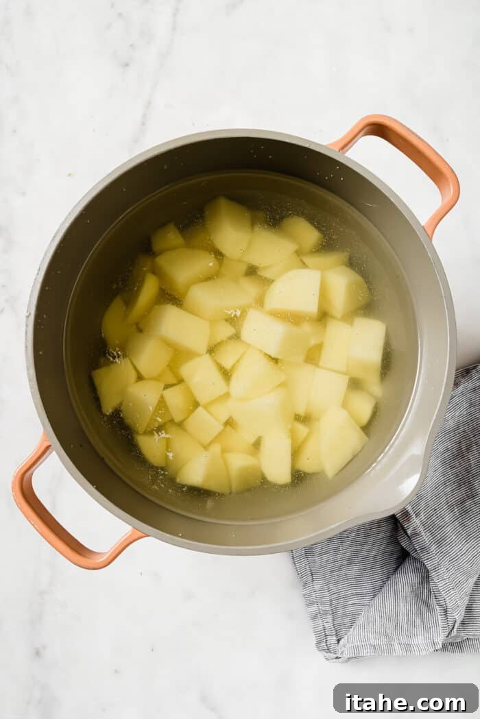 Diced potatoes in a large pot of water on a white countertop. 