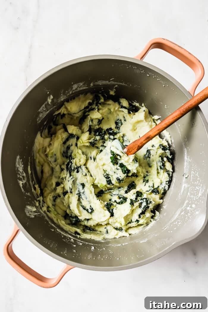 Colcannon in a large pot with a wooden-handled spatula in it. 