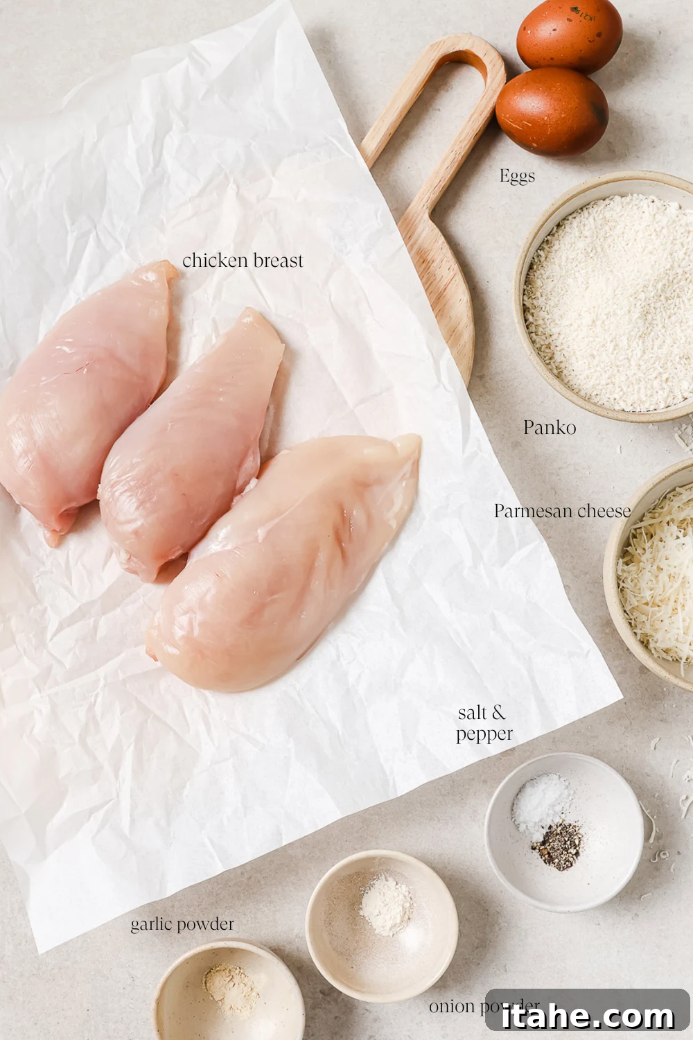 Pre-measured ingredients for air fryer chicken cutlets, including chicken breasts, eggs, Panko breadcrumbs, Parmesan cheese, and seasonings.