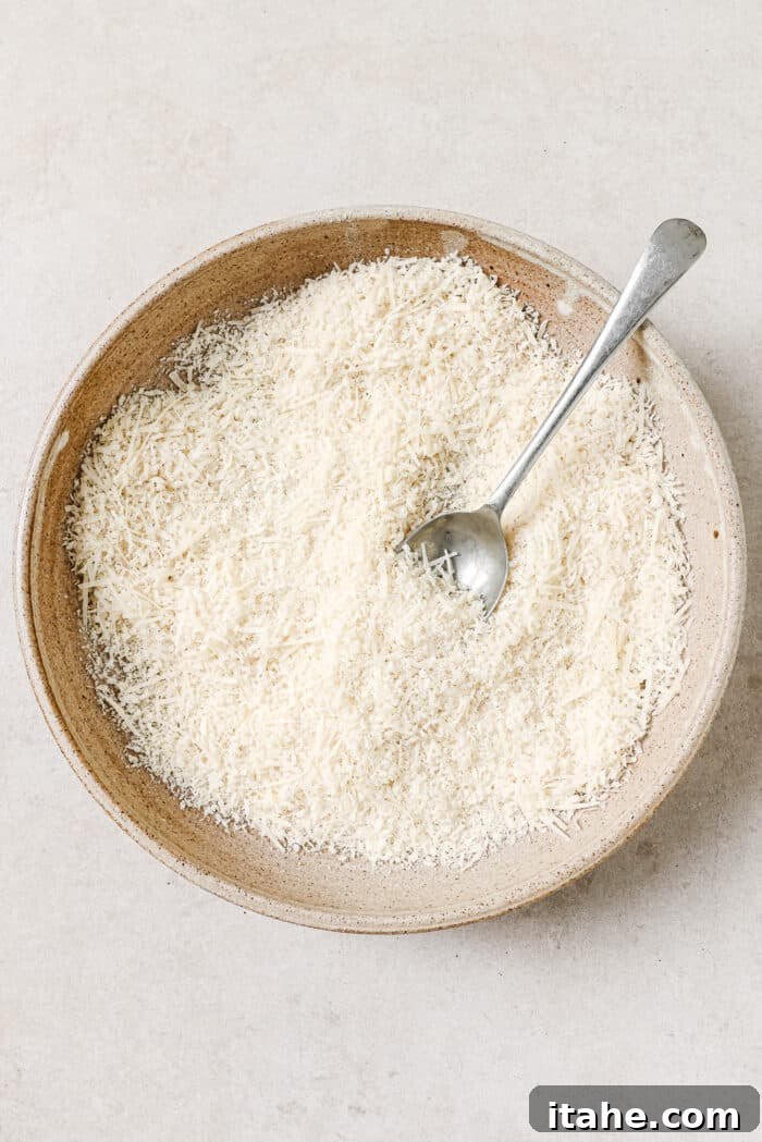 Breadcrumbs, parmesan cheese, and seasonings in a mixing bowl with a spoon in it.