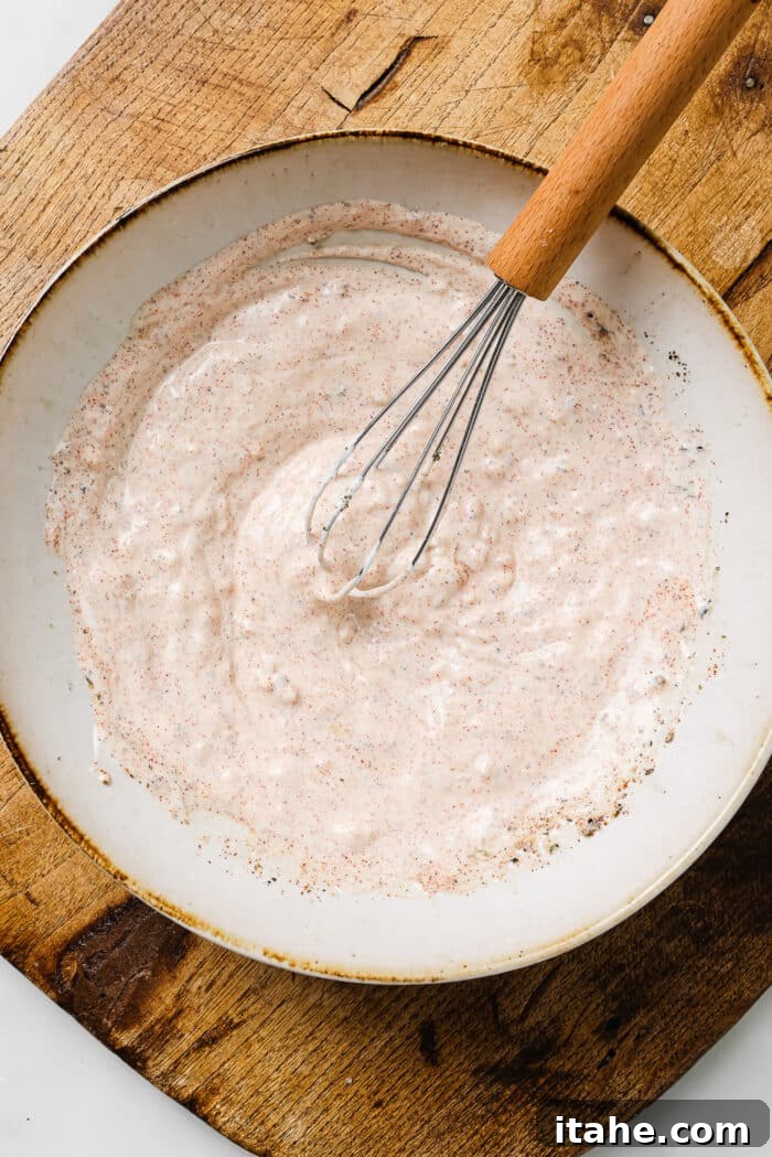 Creamy Yogurt Chicken Breasts 4 Greek yogurt marinade in a white bowl with a whisk in it.