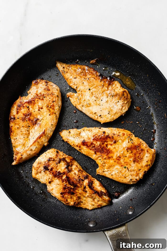Creamy Yogurt Chicken Breasts 7 Four yogurt-marinated chicken breasts searing in a large skillet.