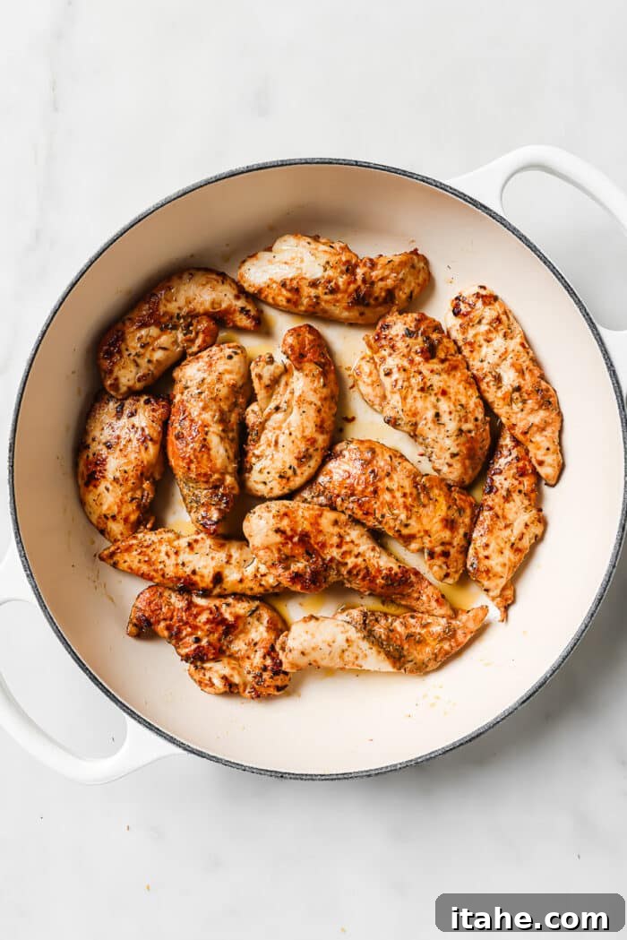 Perfectly cooked and golden-brown chicken tenders resting in a large ceramic cast-iron skillet.