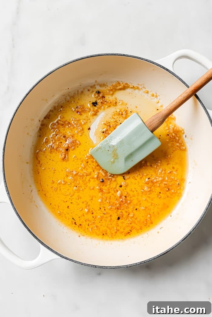 A large ceramic cast-iron pan with melting butter and fragrant minced garlic, ready to be sautéed.