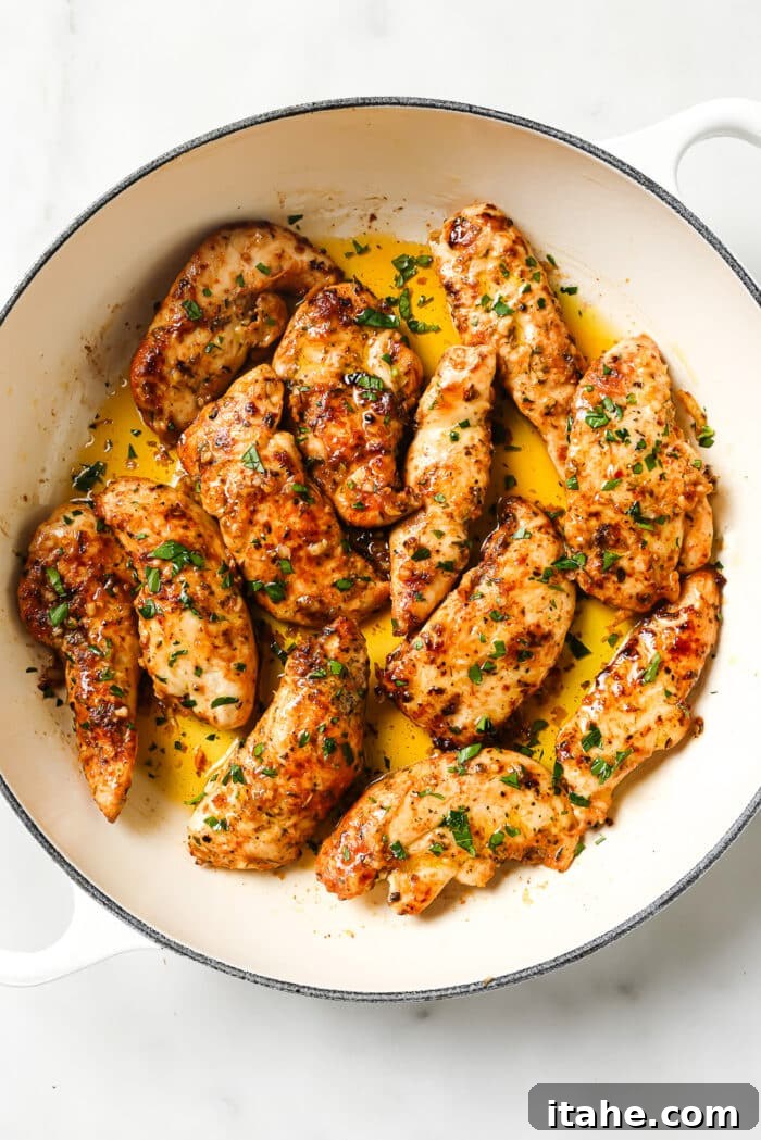 Garlic butter chicken tenders glistening with sauce and garnished with fresh parsley in a ceramic cast-iron skillet, ready to serve.