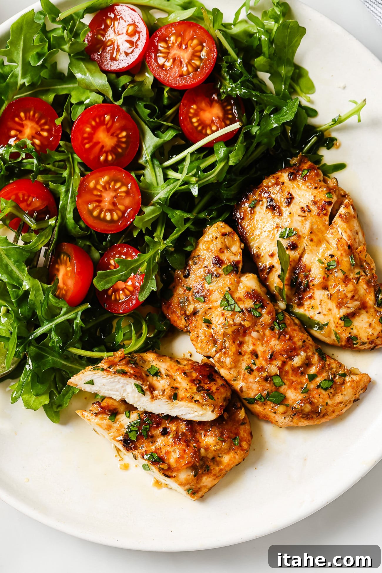 Garlic butter chicken tenders presented elegantly next to a fresh side salad on a pristine white plate.