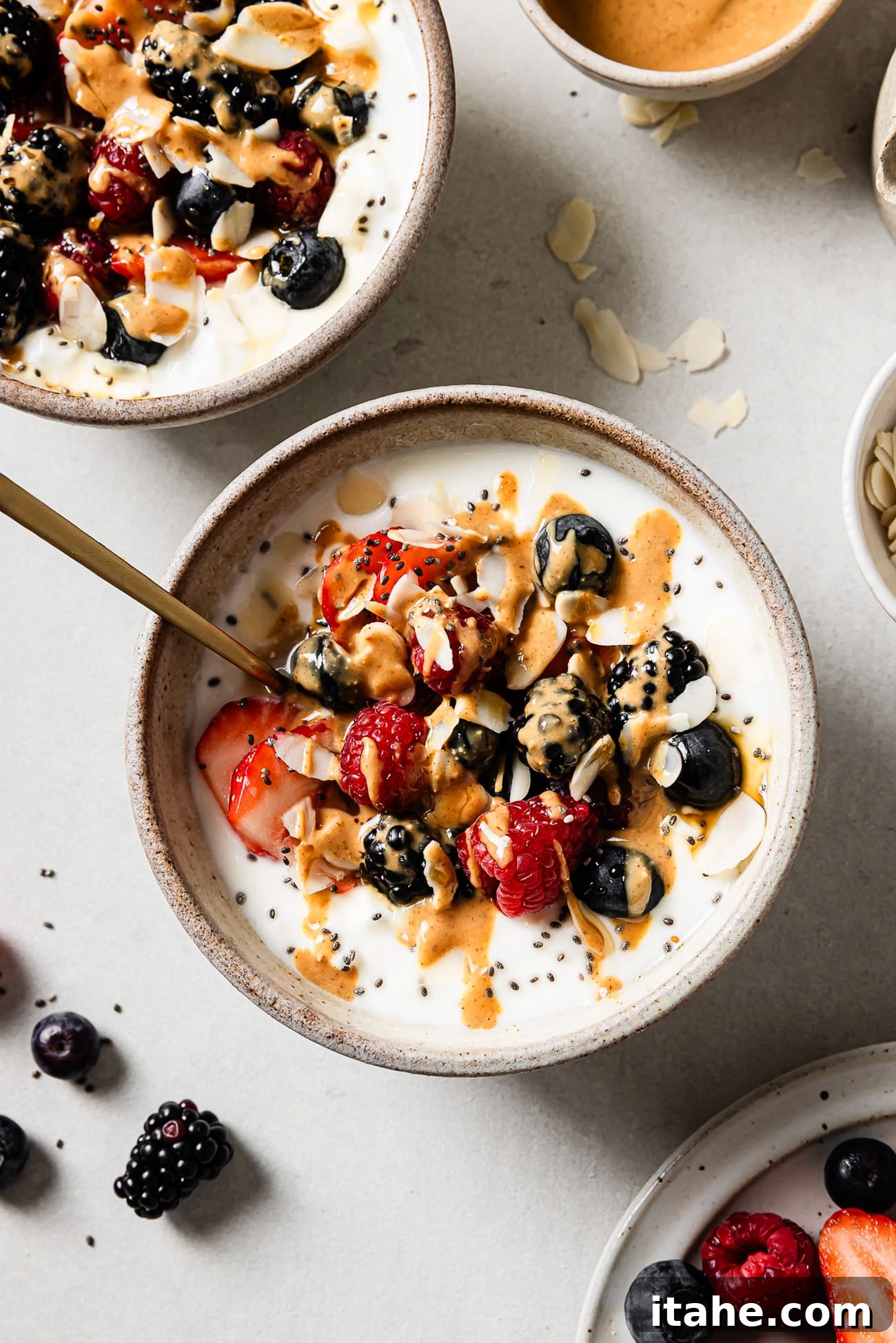 An overhead view of high-protein cottage cheese breakfast bowls topped with mixed berries, chia seeds, nuts, and a drizzle of syrup. 