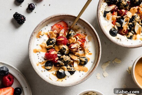 A finished cottage cheese and yogurt breakfast bowl, generously topped with fresh berries, nuts, and a sweet drizzle.