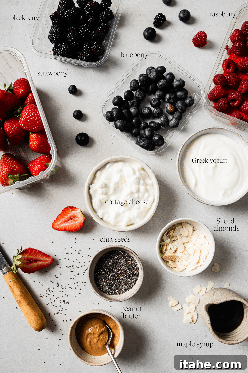 Pre-measured ingredients for a cottage cheese breakfast bowl displayed in small bowls with text overlay labeling each one: cottage cheese, Greek yogurt, mixed berries, chia seeds, sliced almonds, peanut butter, and maple syrup.