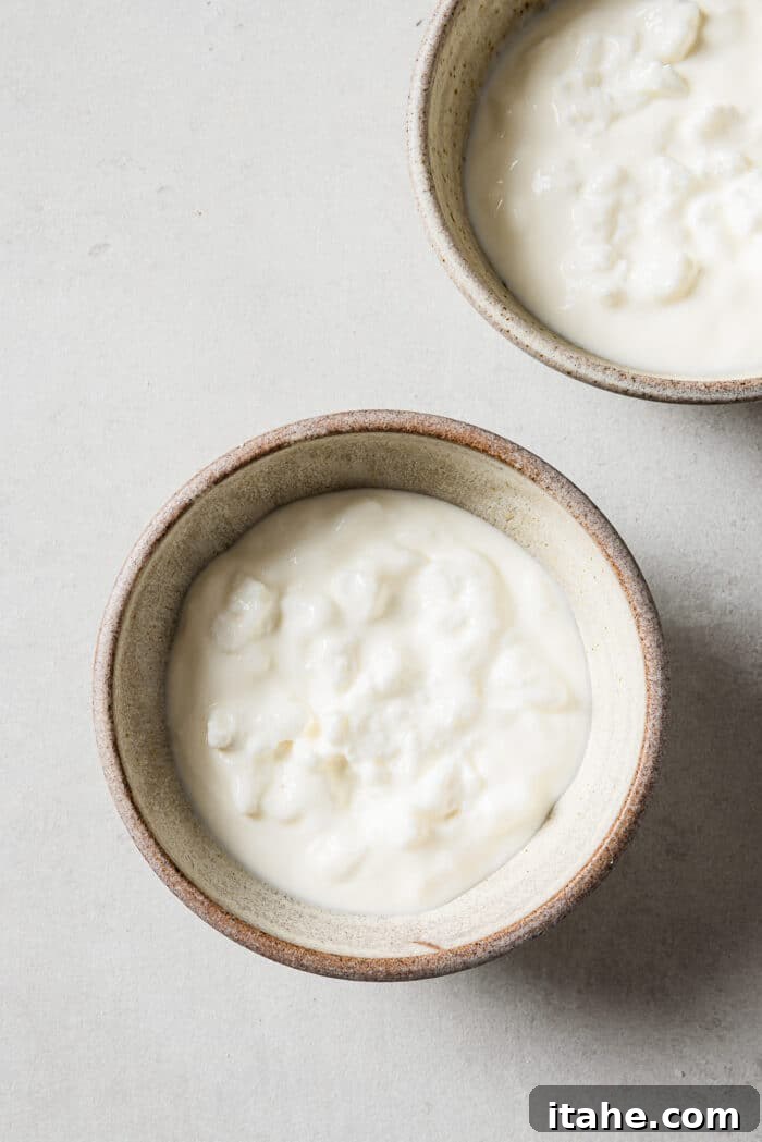 A combination of cottage cheese and Greek yogurt in small serving bowls, ready to be mixed or layered as the base of the breakfast bowl.