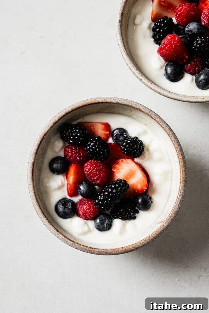 An overhead view of a cottage cheese breakfast bowl topped with a colorful assortment of mixed berries, forming the second layer of the delicious meal.