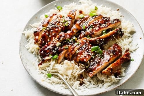 Teriyaki chicken served on a white plate with rice.