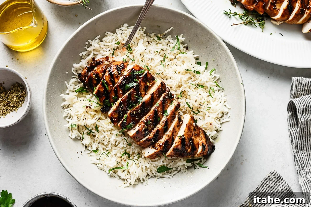 Sweet and Tangy Balsamic Chicken 10 Balsamic chicken served over white rice on a white plate, garnished with fresh herbs.