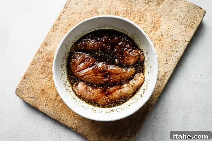 Sweet and Tangy Balsamic Chicken 5 Balsamic marinade and raw chicken breast in a white bowl, ready for marinating.