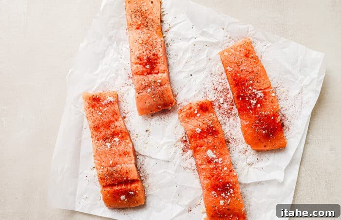 Overhead view of raw, seasoned salmon fillets resting on a paper towel on the kitchen countertop.