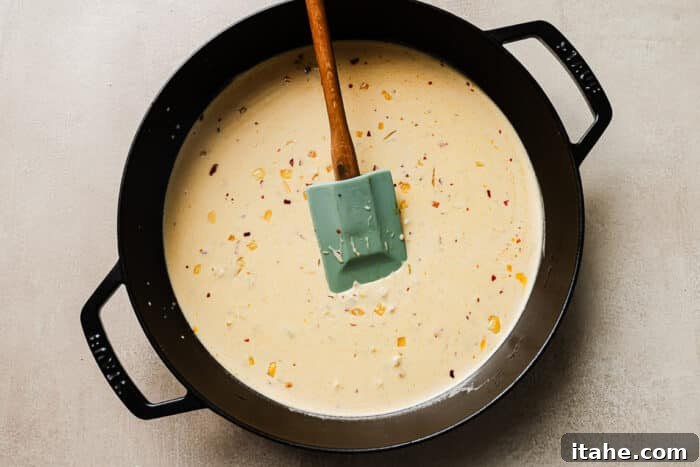 Creamy marry me sauce simmering in a cast iron skillet, with sun-dried tomatoes.