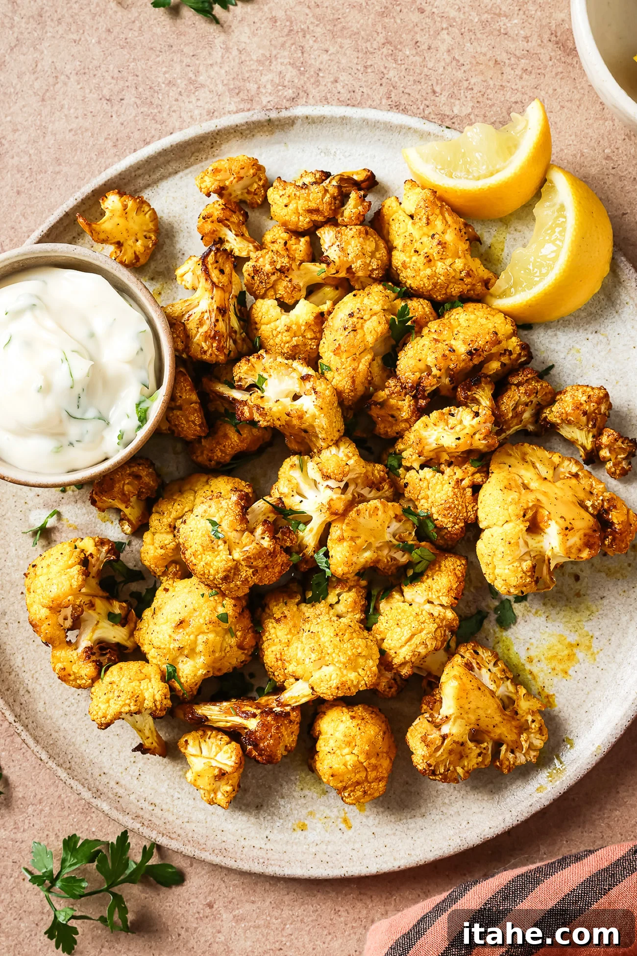 Crispy Roasted Air Fryer Cauliflower 2 Overhead view of crispy air-fried cauliflower on a white plate, garnished with fresh herbs.