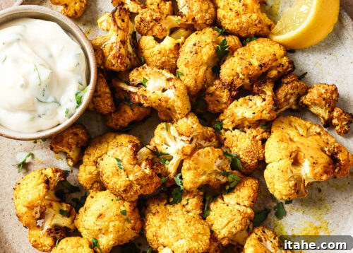 Overhead view of crispy air-fried cauliflower on a white plate, ready to be served and garnished.