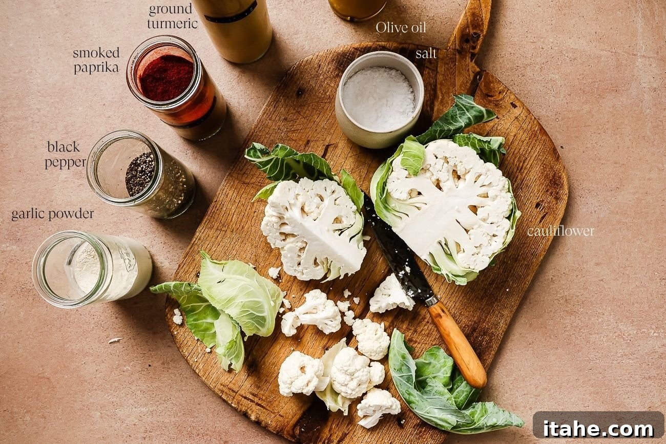 Crispy Roasted Air Fryer Cauliflower 3 Ingredients laid out on a wooden board to make air fryer cauliflower, including a whole cauliflower, olive oil, and various spices.