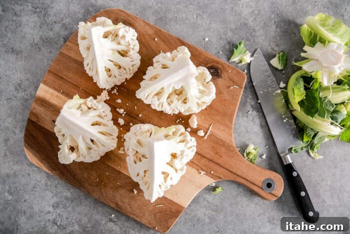 Crispy Roasted Air Fryer Cauliflower 6 Cauliflower head cut into four quarters on a wooden board, ready for core removal.