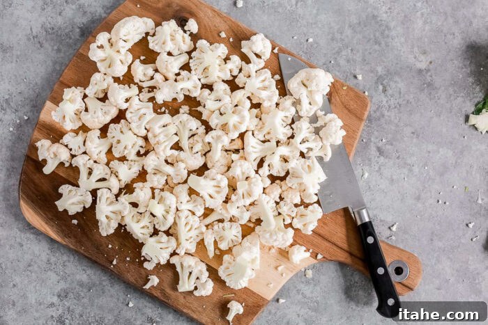 Crispy Roasted Air Fryer Cauliflower 7 Loose cauliflower florets on a wooden board, some larger, some smaller.