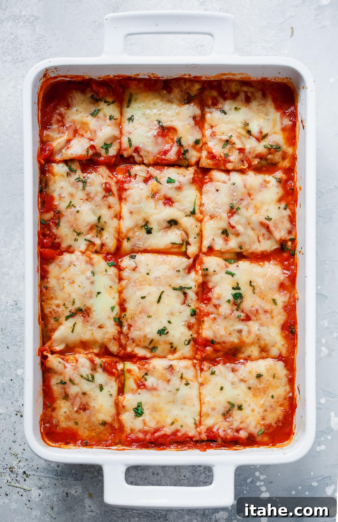 Noodle-Free Zucchini Lasagna 2 Overhead view of a golden-brown Zucchini Lasagna in a white casserole dish, garnished with fresh herbs.