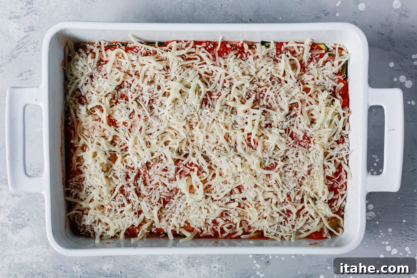 Noodle-Free Zucchini Lasagna 8 Overhead view of an assembled Zucchini Lasagna, topped with mozzarella and Parmesan cheese, ready for the oven.